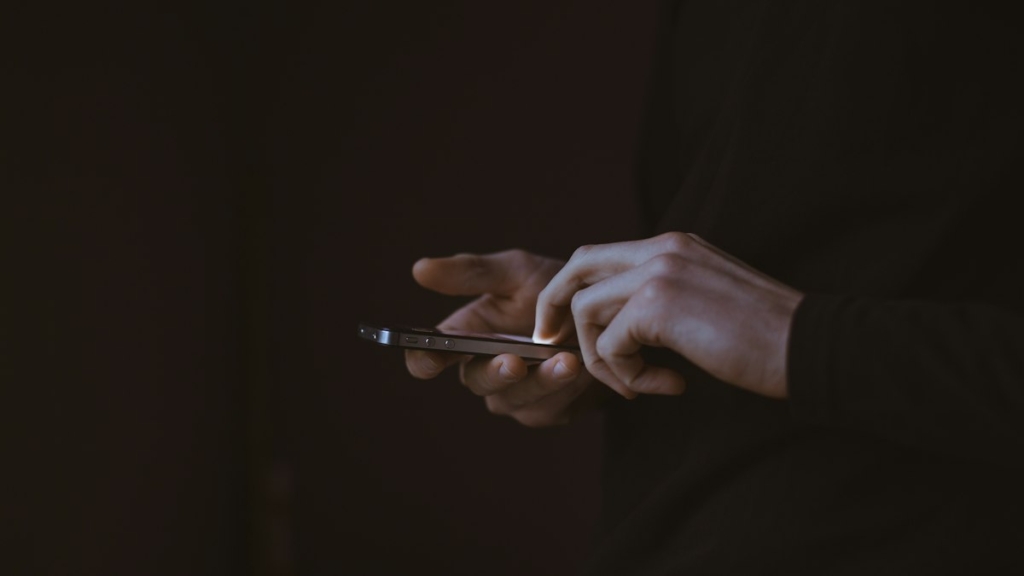 Gün batımında elinde akıllı telefon tutan kişinin silüeti