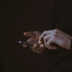 Gün batımında elinde akıllı telefon tutan kişinin silüeti
