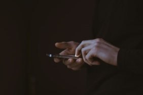 Gün batımında elinde akıllı telefon tutan kişinin silüeti